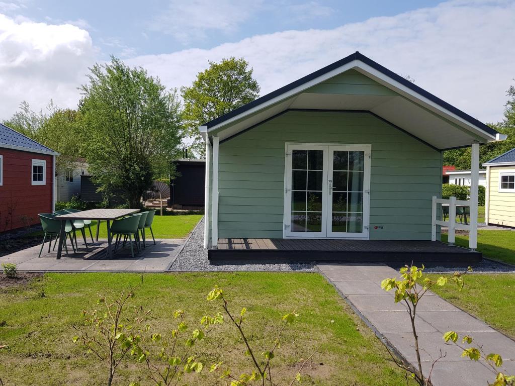 a small green house with a table in a yard at De Bijsselse Enk, Noors chalet 15 in Nunspeet