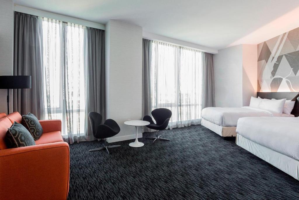 een hotelkamer met 2 bedden en een tafel en stoelen bij Courtyard by Marriott Long Island City/New York Manhattan View in Queens