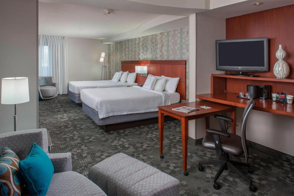 a hotel room with a bed and a desk with a tv at Courtyard by Marriott Nashville Goodlettsville in Goodlettsville