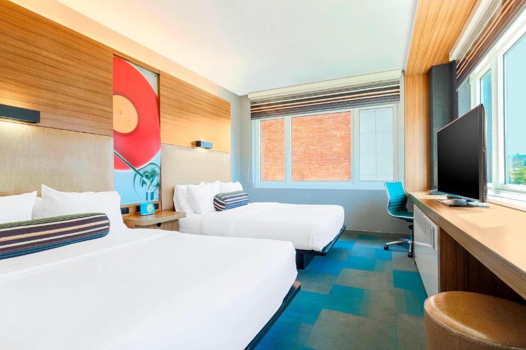 a hotel room with two beds and a flat screen tv at Aloft Harlem in New York