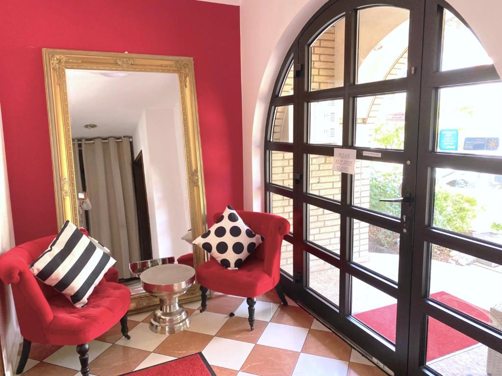 a living room with red chairs and a mirror at VILLA ORCHARD Frankfurt in Zeilsheim