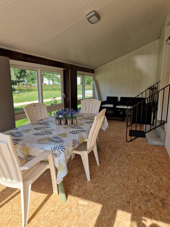 - une table à manger avec des chaises blanches et des fleurs dans l'établissement Gîte Pauline, à Saint-Martial-de-Valette