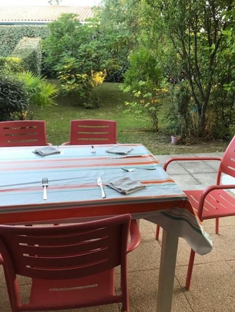 une table avec des chaises rouges et un chiffon de table bleu et blanc dans l'établissement T3, jardin privatif, 2 chambres, Côte Basque (Anglet), à Anglet