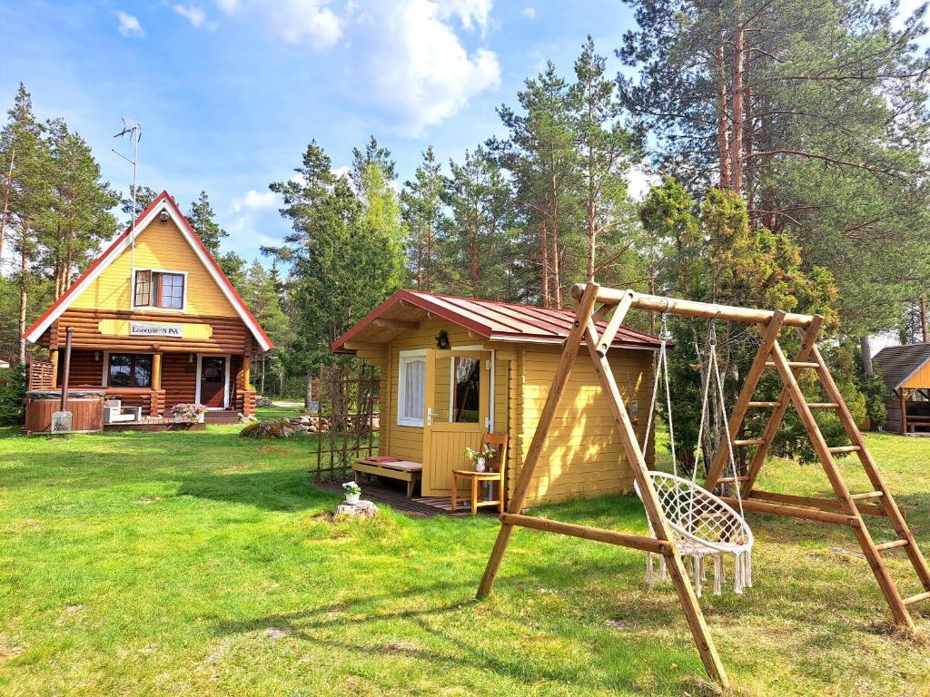 una pequeña casa amarilla con un columpio en el patio en Lootuse Spa, en Nõmmemaa