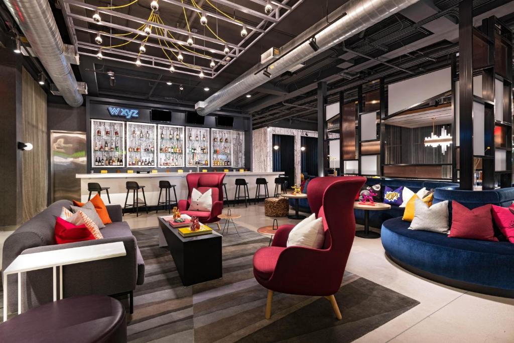 a lobby with couches and chairs and a bar at Aloft San Antonio UTSA Area in San Antonio