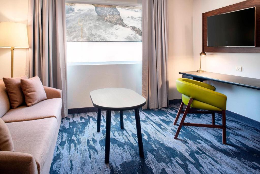 a hotel room with a couch and a table and a chair at Fairfield Inn & Suites by Marriott Tijuana in Tijuana