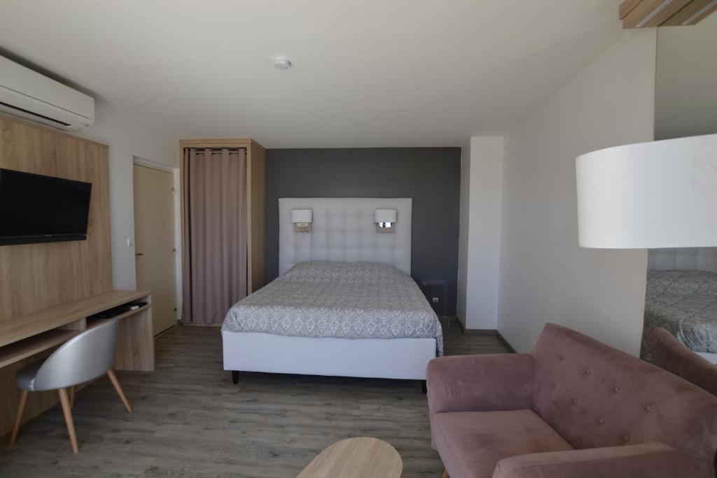 une chambre d'hôtel avec un lit et un canapé dans l'établissement Studio Ève Résidence Naturiste Le Jardin D'Eden, au Cap d'Agde