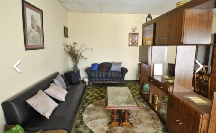 a living room with a black couch and a table at House of creations in Diepkloof