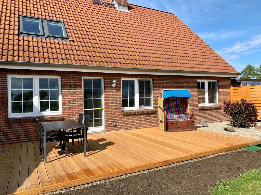 a deck with a table and a chair and a house at Sundblick, ideal für Familien in Teschendorf