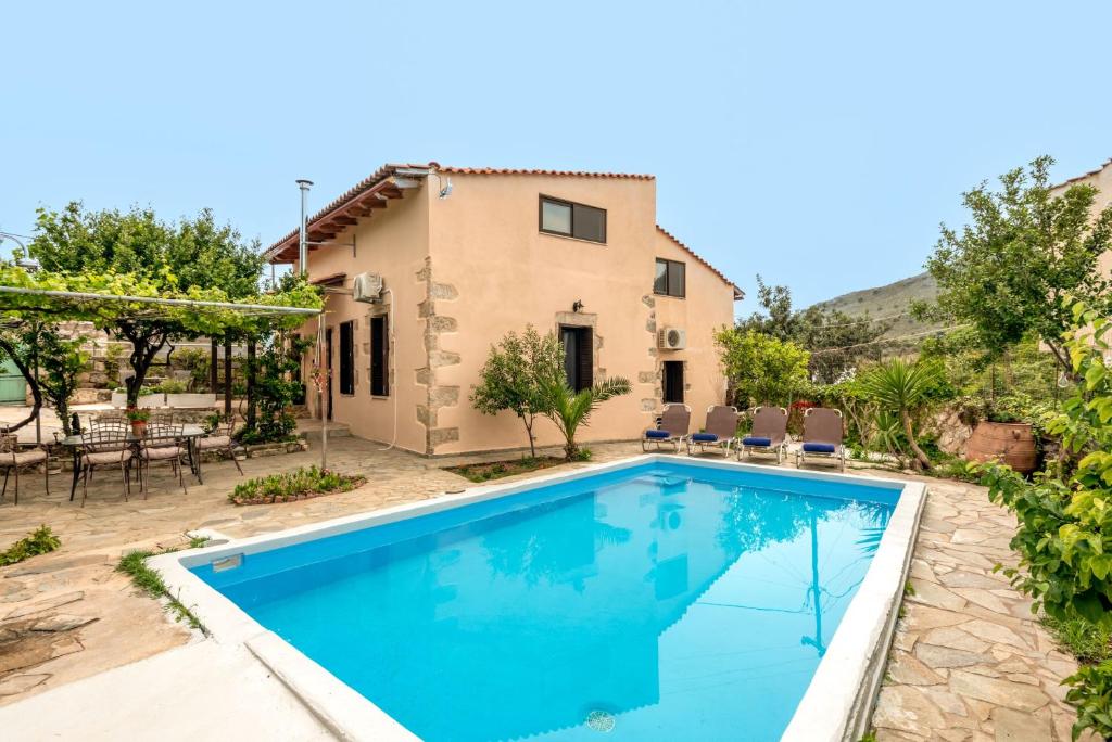 a villa with a swimming pool in front of a house at Joel Living Collection - Rustic Villa in Áptera