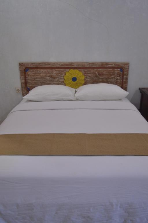 a bed with a yellow flower on the head board at hotel batukaras kalaras in Batukaras