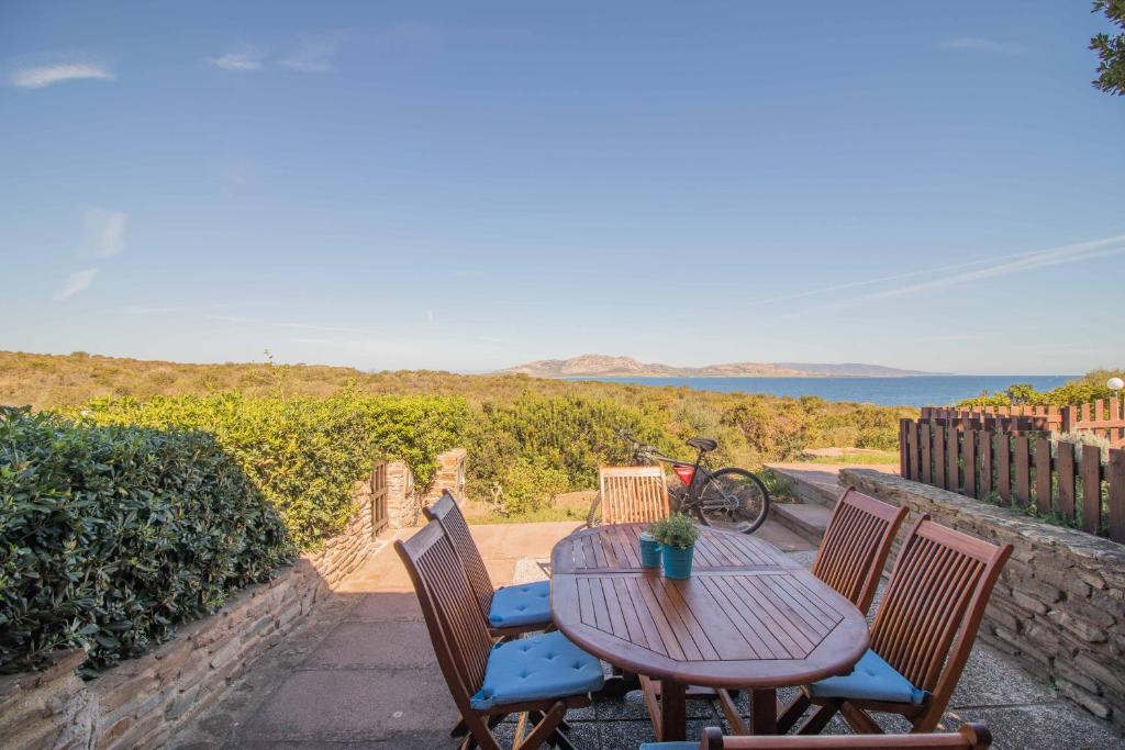 a wooden table and chairs with a view of the ocean at Casa Pace Stintino in Stintino