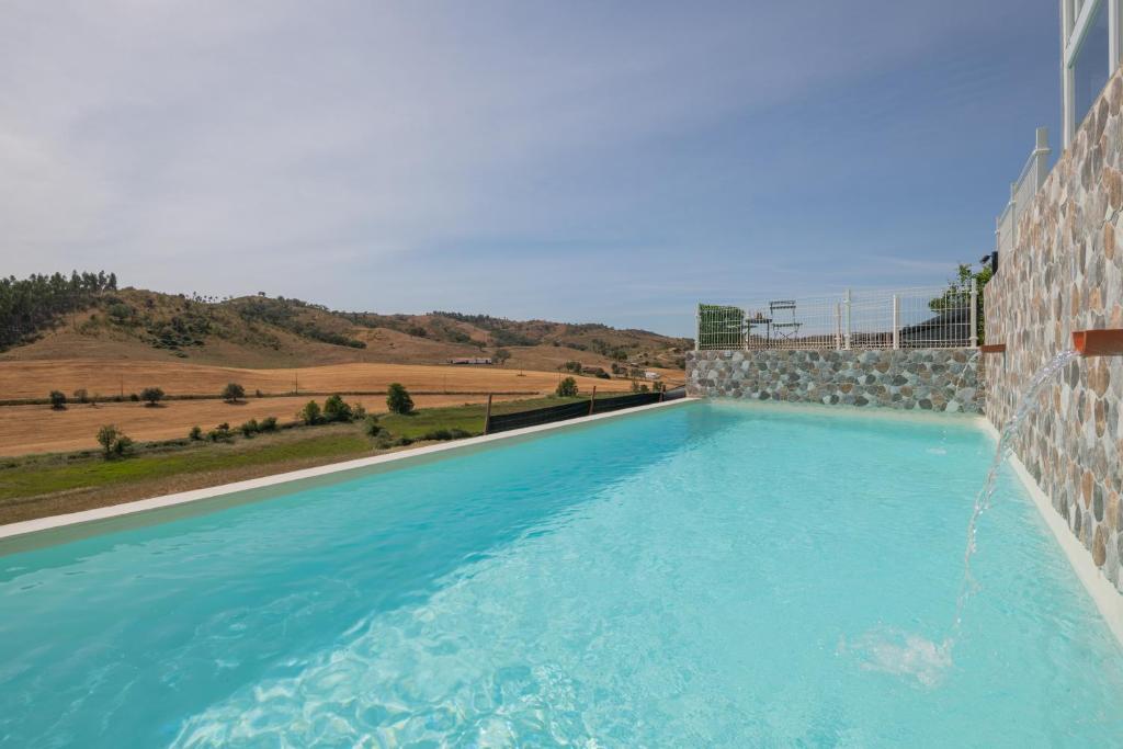 een zwembad met blauw water in een gebouw bij Monte Corte Enchária in São Teotónio