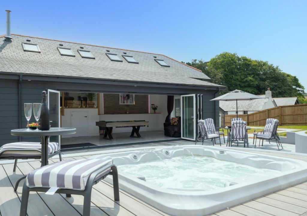 a hot tub on a deck with a table and chairs at Bowjy in Menheniot