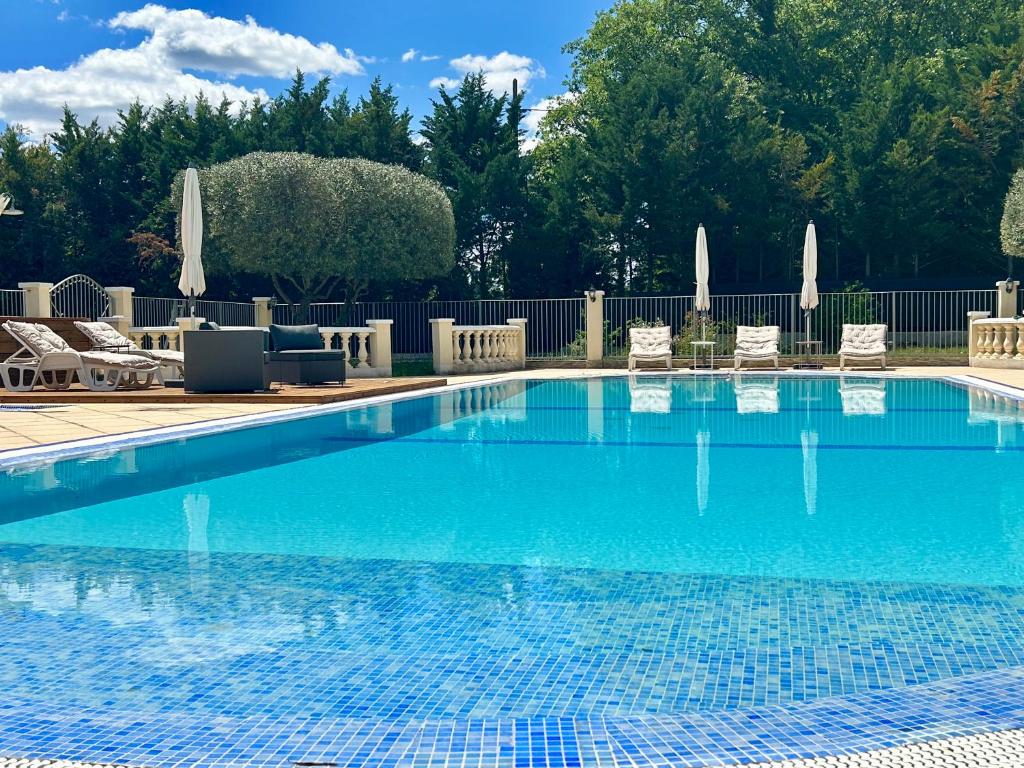 una piscina azul con sillas y una valla en LES TERRASSES DE VALERIAN, en Brignoles