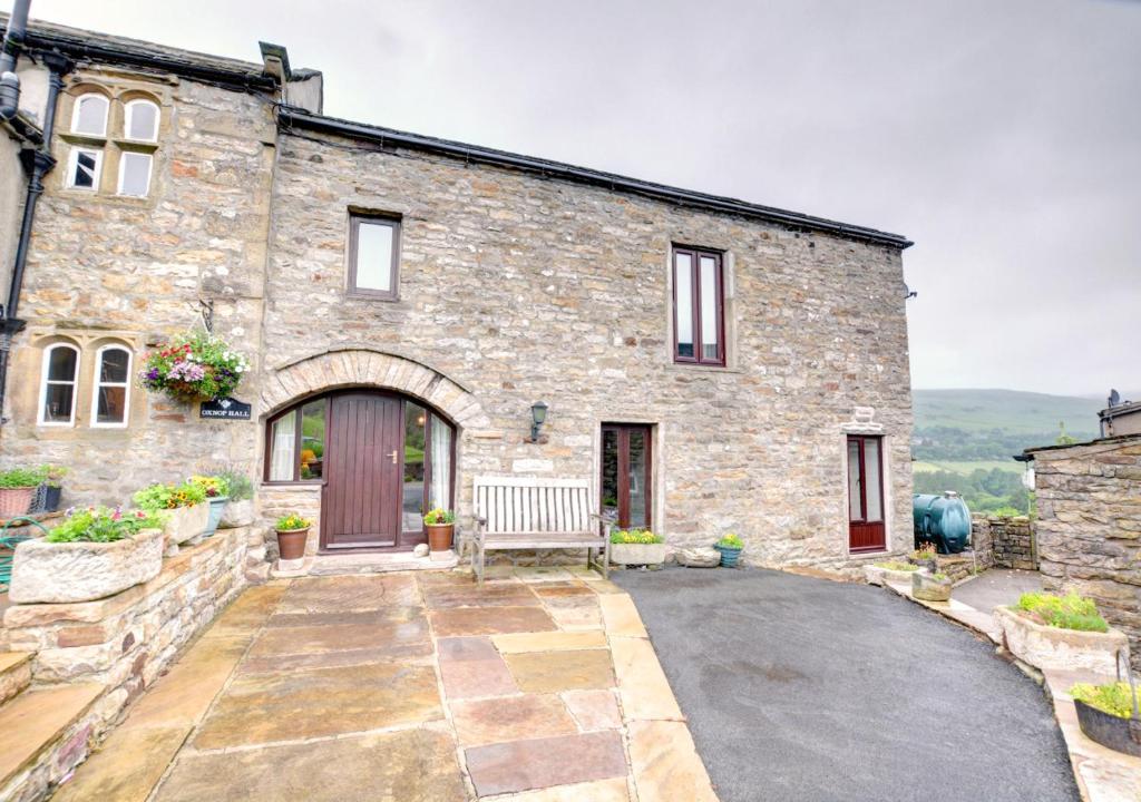 a stone building with a bench in front of it at Oxnop Cottage in Gunnerside