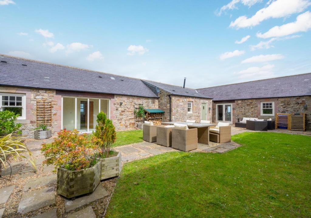 a backyard of a stone house with a patio at The Barns in Ellingham