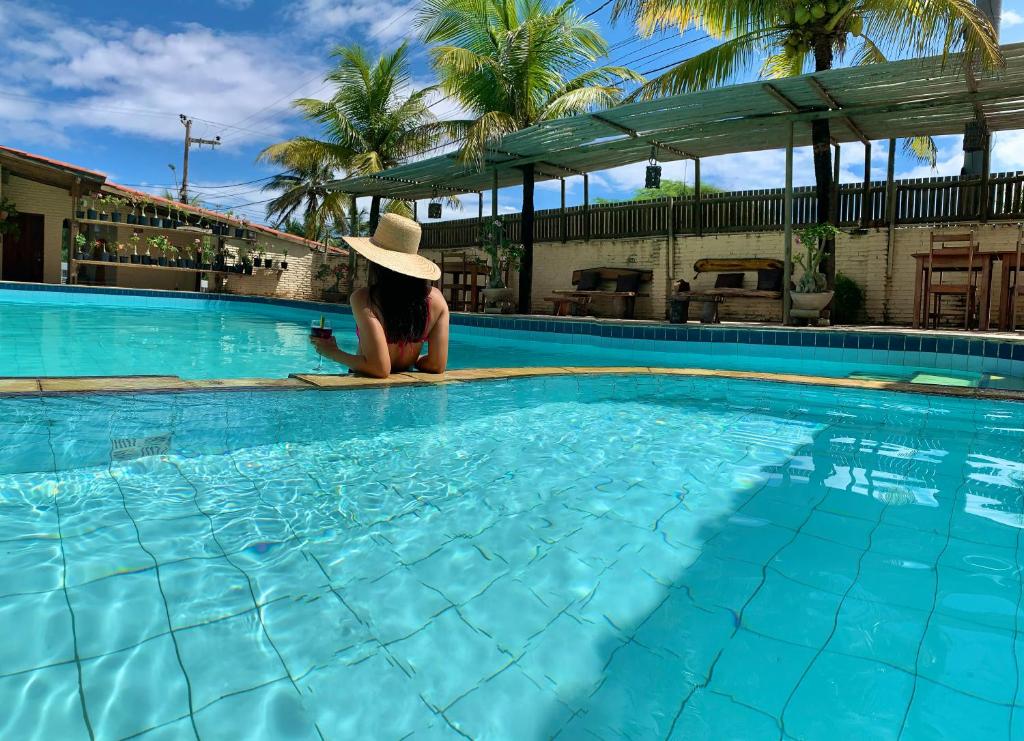 a woman in a hat sitting in a swimming pool at Pousada Borboleta in Canoa Quebrada