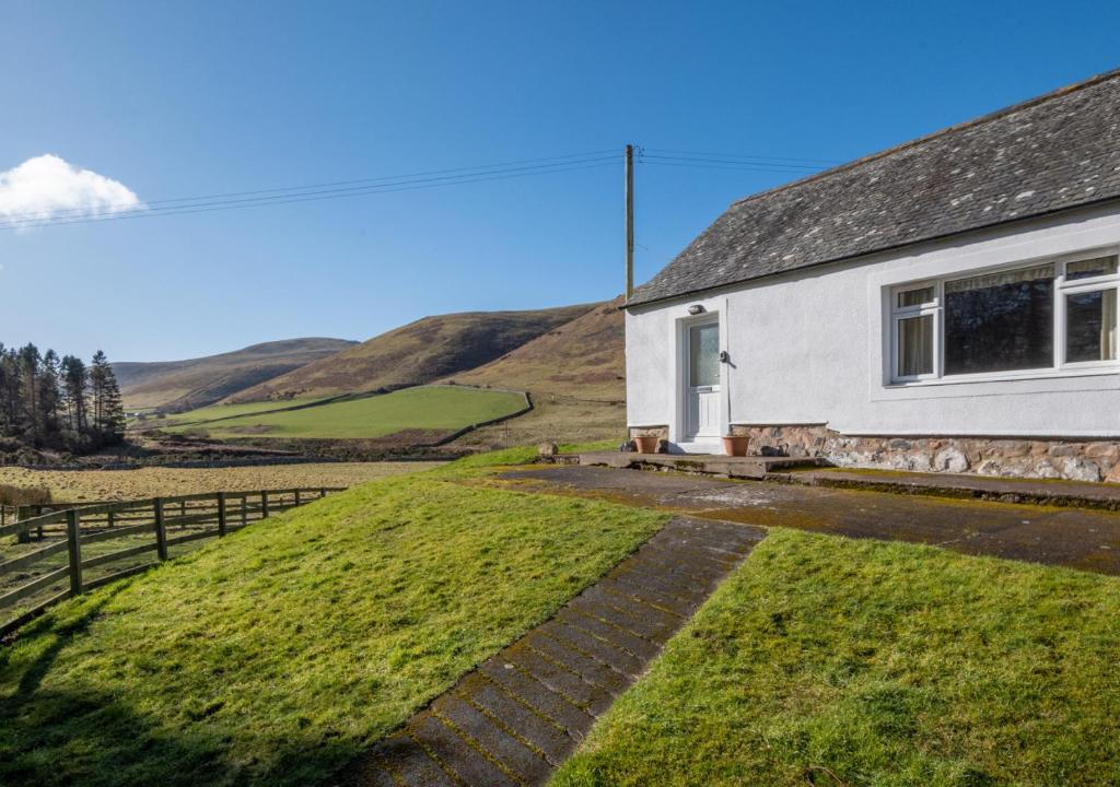 a white house with a hill in the background at The School House in Kirknewton