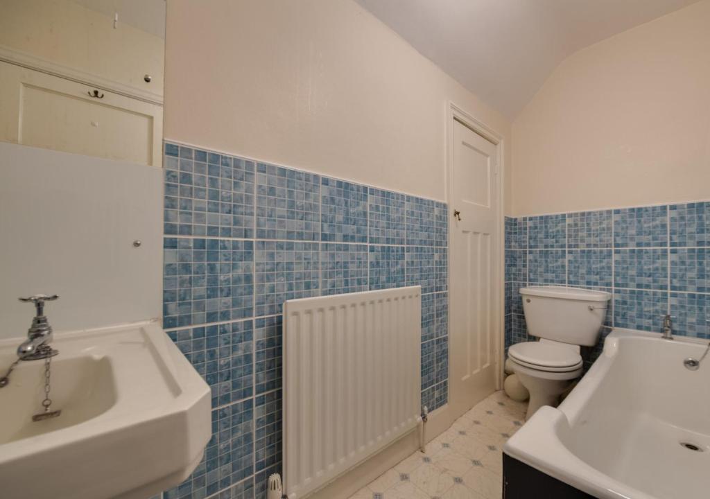 bagno piastrellato blu con lavandino e servizi igienici di Rookery Nook a Warkworth