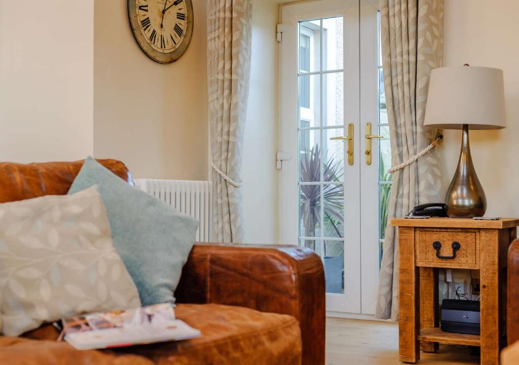 a living room with a couch and a clock on the wall at Waters Edge - Warkworth in Warkworth