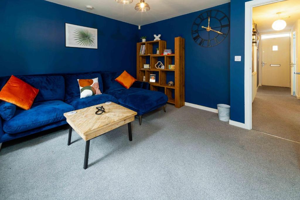 a blue living room with a blue couch and a table at Ideal Lodgings In Openshaw in Manchester