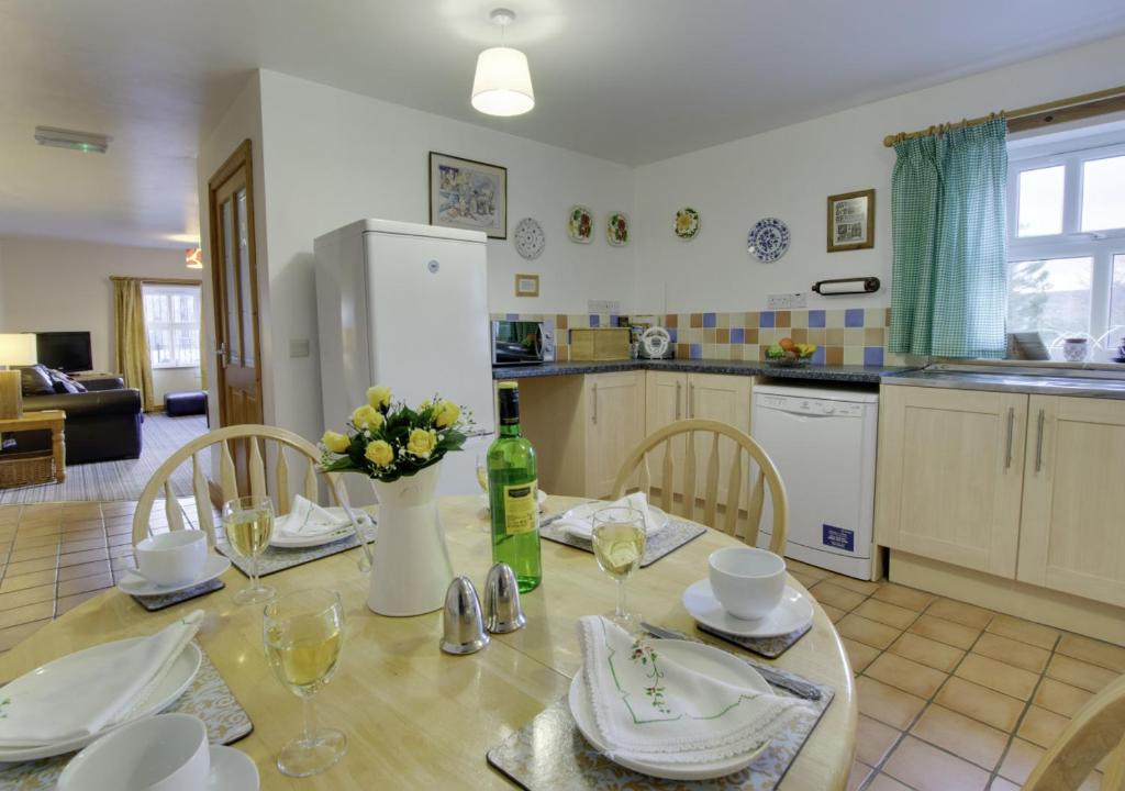 uma cozinha com uma mesa e uma garrafa de vinho em Alices Cottage em Lanehead