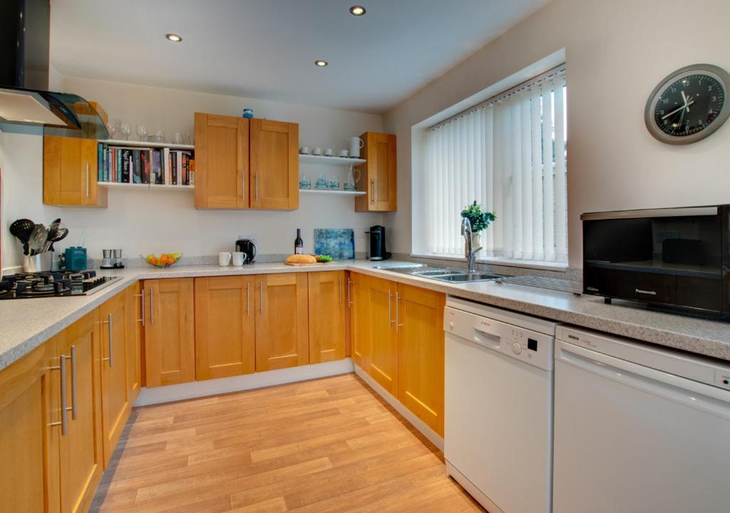a large kitchen with wooden cabinets and a microwave at Monkey Puzzle Retreat in Belford