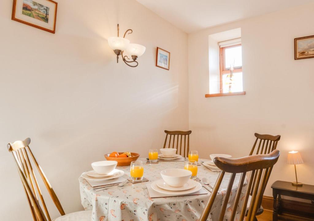 a dining room with a table with chairs and a tablecloth on it at Bede Cottage in Chatton