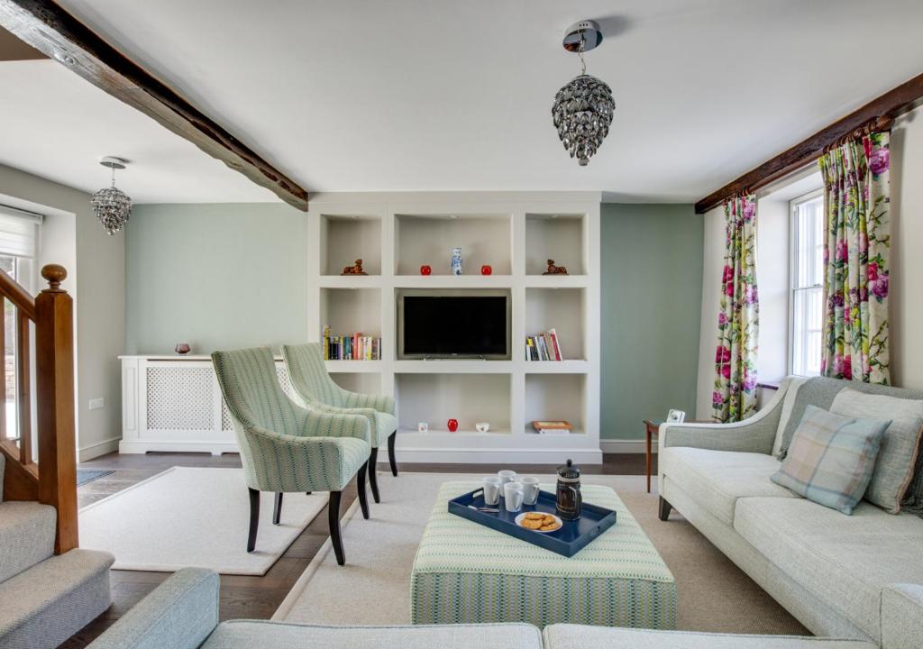 a living room with a couch and chairs and a tv at Memories Cottage in Milnthorpe