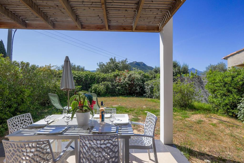 una mesa con sillas y una sombrilla en el patio en Maison Fab Jo - Proche de lîle rousse, en Belgodère