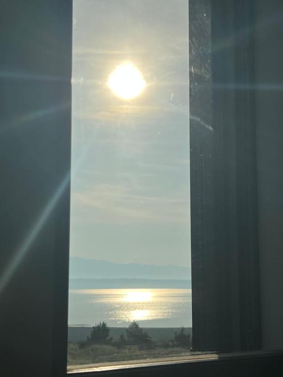 a window with a view of the ocean and the sun at Apartments Linic in Nin