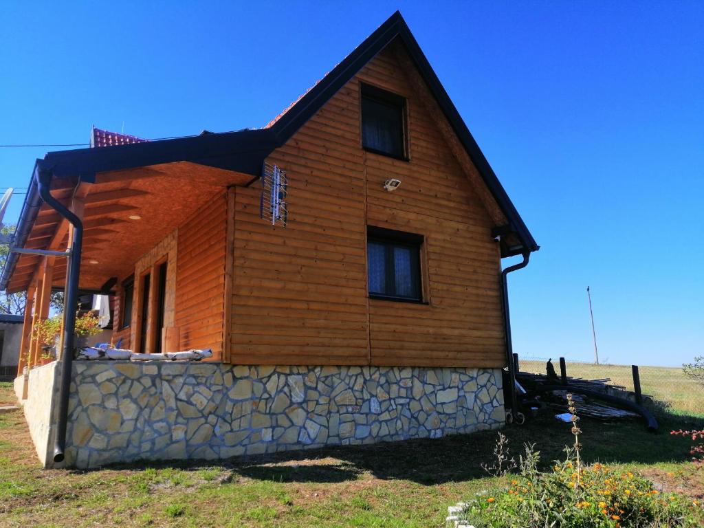 a wooden house with a stone wall at Tarin zov in Kaludjerske Bare