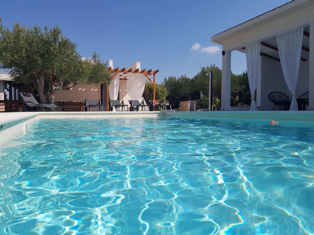 a swimming pool with blue water in front of a house at Dalmatian stone house with swimming pool near Supetar in Supetar