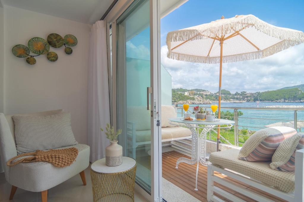 um quarto com uma varanda com uma mesa e um guarda-chuva em Tango Apartment On The Beach em Paleokastritsa