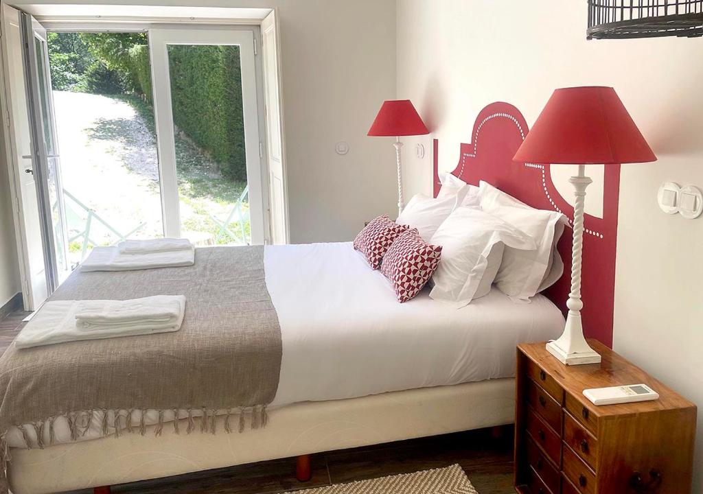 a bedroom with a bed with two lamps and a window at Eighteen21 Houses - Casa da Mula in Quinta Velha in Sintra