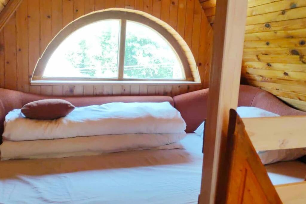 a bed in a room with a window at Romanticka chata pre hostí s ohniskom in Spišská Nová Ves