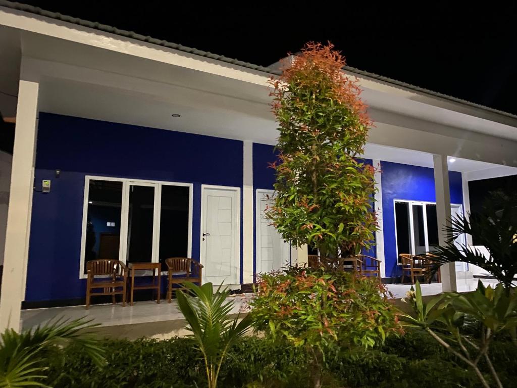 a house with a blue wall and chairs in it at Danke Lodge in Labuan Bajo