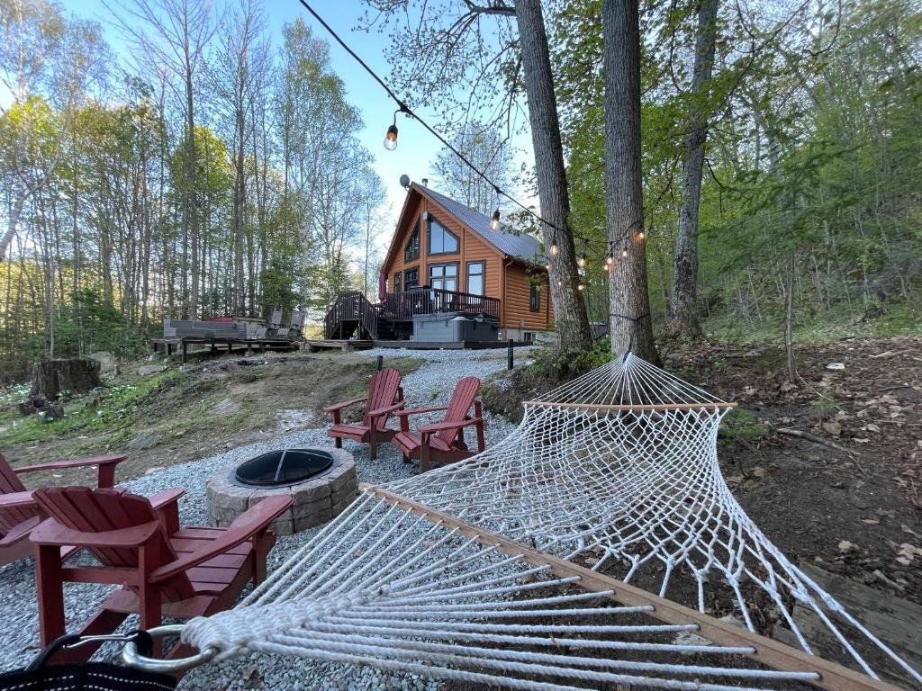 a hammock in front of a log cabin at Joy's Chalet - Hottub, Lake, & Cottage in Val-des-Bois