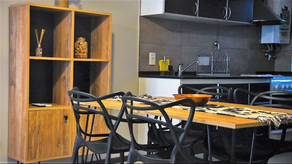 a kitchen with a wooden table and black chairs at Departamentos amoblados de Jardines de Libertador in San Juan