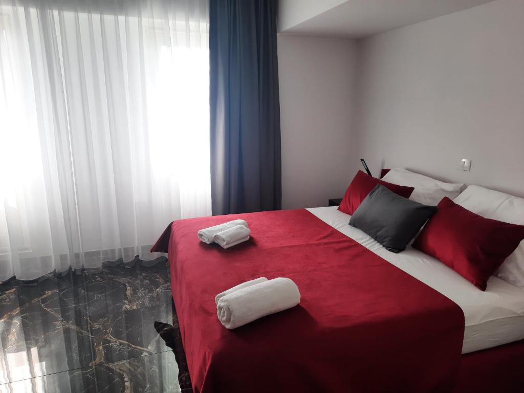 a bedroom with a red and white bed with towels on it at Hotel Prunk in Sežana