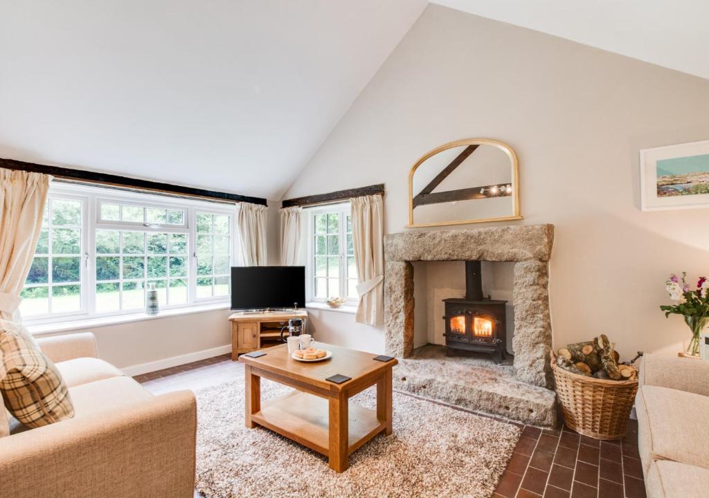 a living room with a fireplace and a couch at Troutstream in Saint Tudy