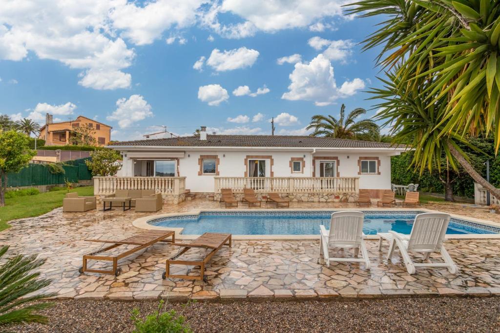 a swimming pool with two chairs and a house at Villa Terrassa in Sant Antoni de Calonge