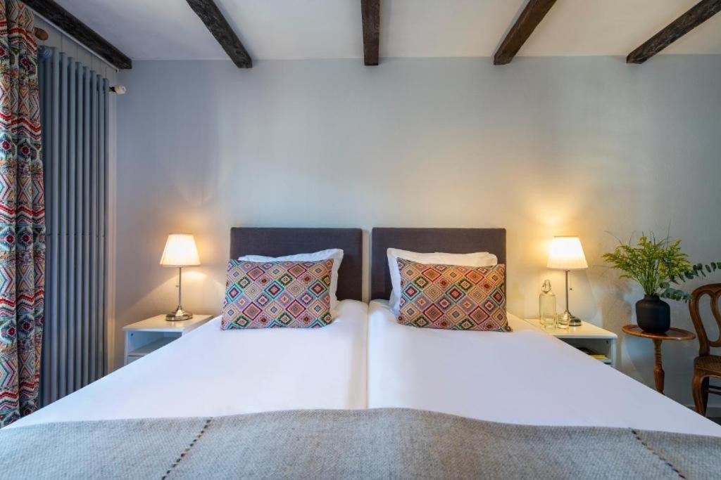 a bedroom with a large white bed with two lamps at Hotel de La Poste in La Tzoumaz