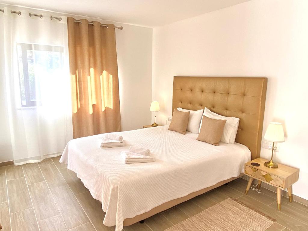 Un dormitorio con una gran cama blanca y una ventana en Quinta das Andorinhas, en Carvoeiro