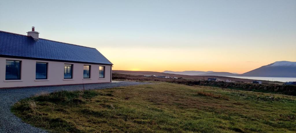 a house on a hill with the sunset in the background at Fal Mor House in Belmullet