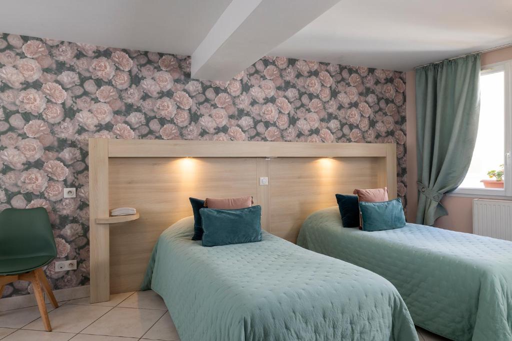 a bedroom with two beds and a wall with flowers at Hôtel de Lion sur Mer in Lion-sur-Mer