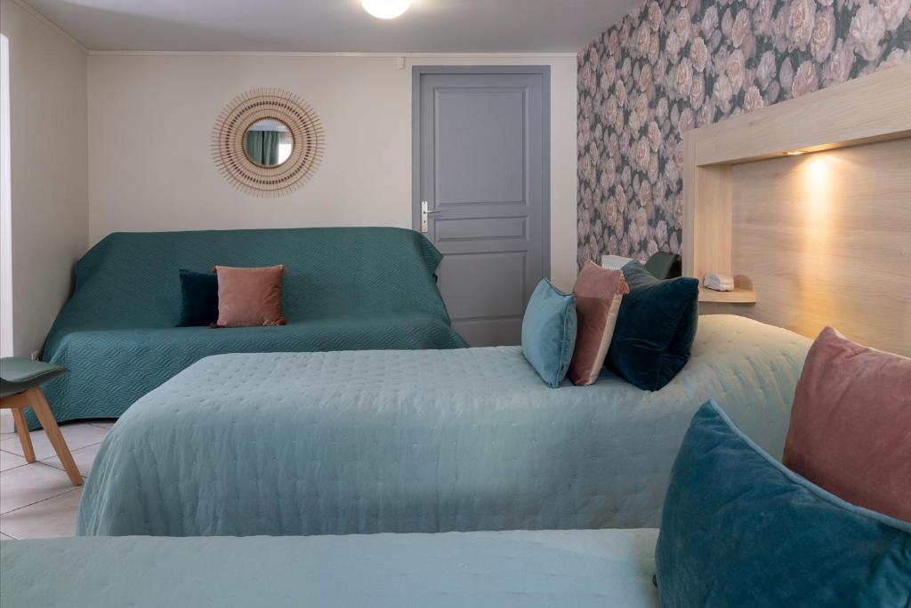a bedroom with two beds and a green couch at Hôtel de Lion sur Mer in Lion-sur-Mer