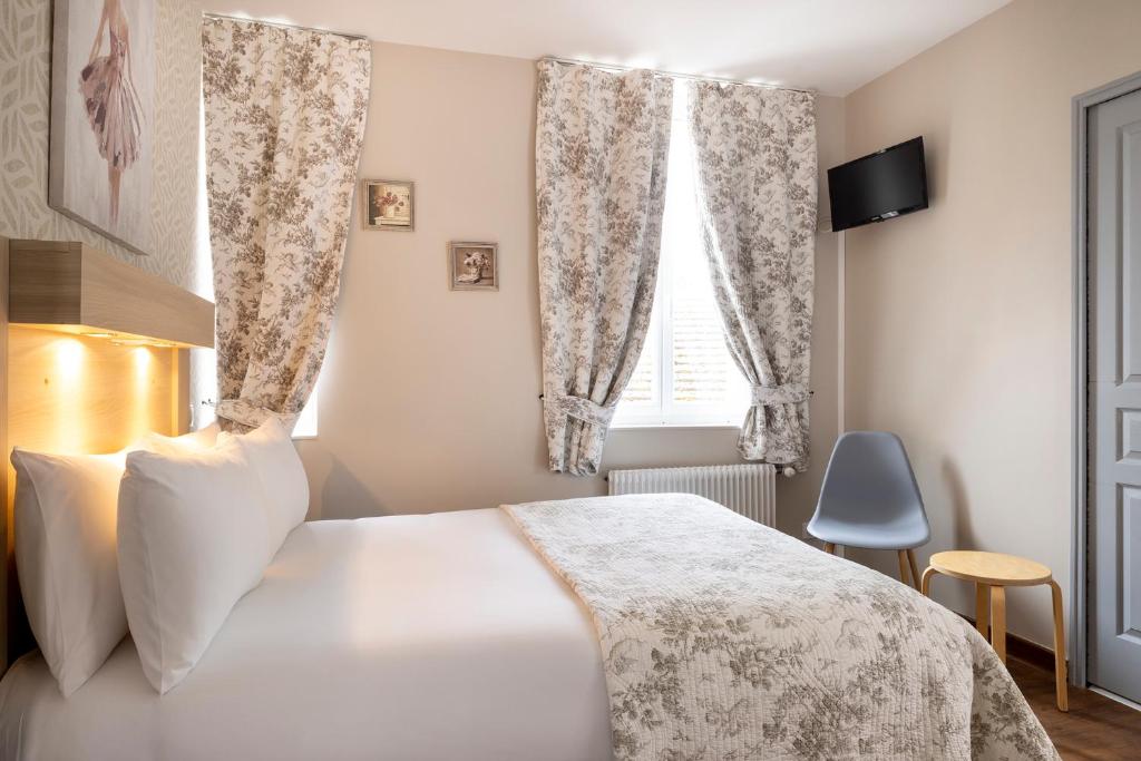 a bedroom with a white bed and a window at Hôtel de Lion sur Mer in Lion-sur-Mer