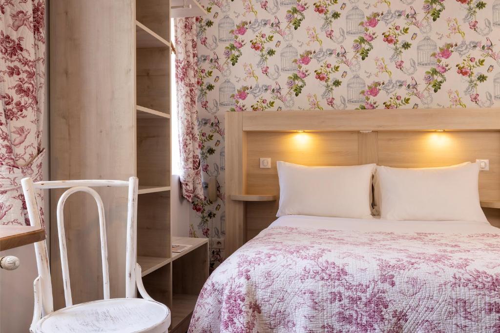 a bedroom with a bed and a chair at Hôtel de Lion sur Mer in Lion-sur-Mer